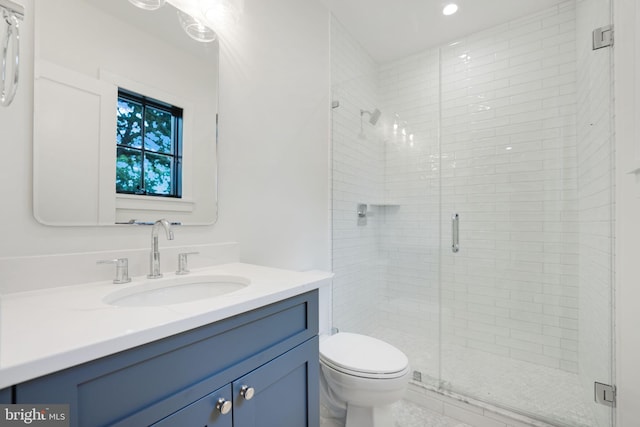 bathroom featuring a shower with shower door, vanity, and toilet