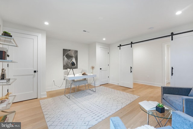 home office with a barn door and light wood-type flooring