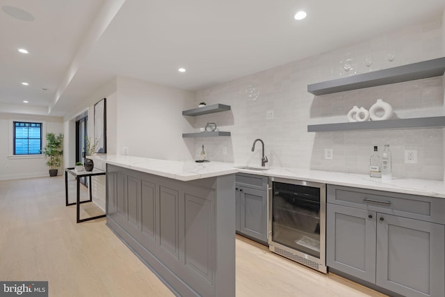 bar with light hardwood / wood-style flooring, wine cooler, light stone counters, and backsplash