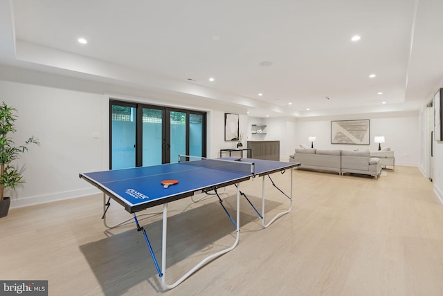 recreation room featuring a raised ceiling and light hardwood / wood-style flooring