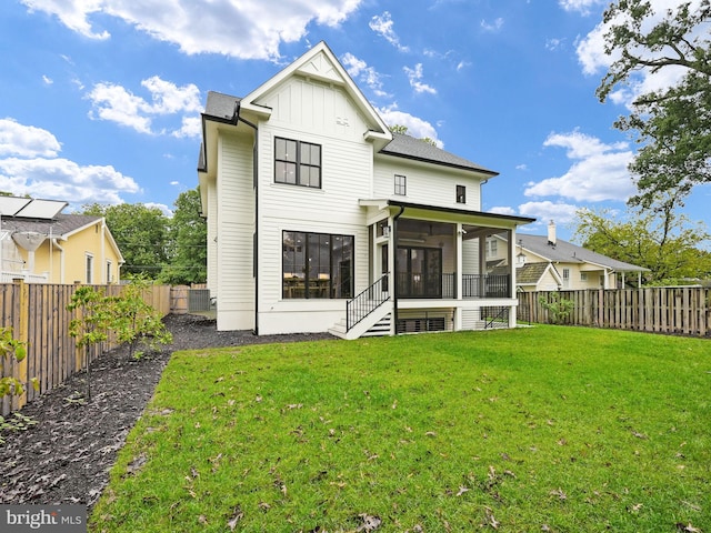 rear view of house with a lawn and a sunroom