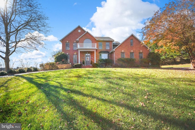 view of property with a balcony and a front yard