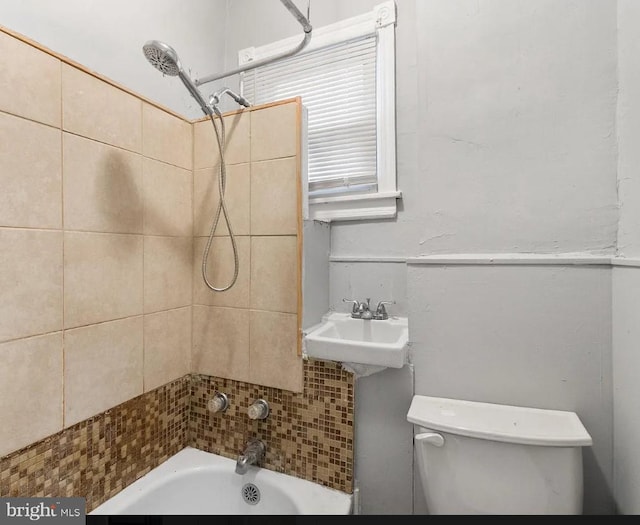 full bathroom with sink, tiled shower / bath, and toilet