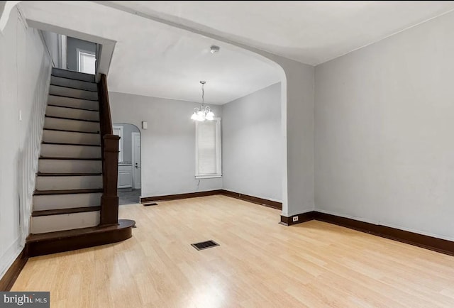 empty room with light hardwood / wood-style flooring and a chandelier