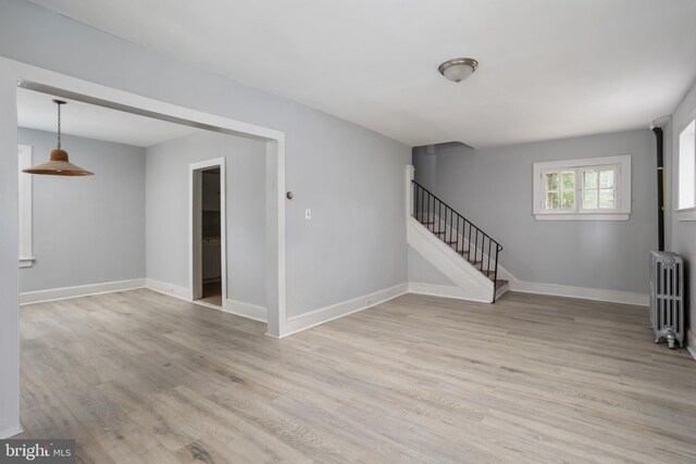 unfurnished room featuring light hardwood / wood-style floors and radiator heating unit