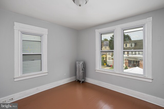 empty room featuring dark hardwood / wood-style floors and radiator heating unit