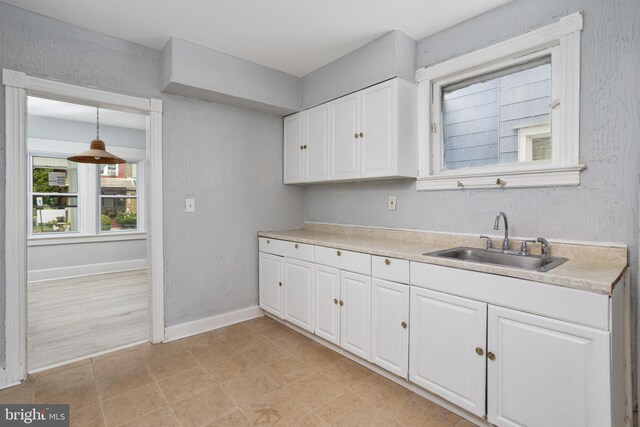 kitchen featuring white cabinetry, sink, and decorative light fixtures