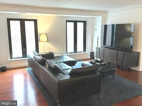 living room featuring a wealth of natural light, wood-type flooring, french doors, and crown molding