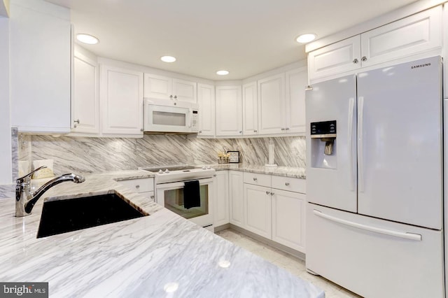 kitchen featuring sink, white cabinetry, decorative backsplash, white appliances, and light stone countertops