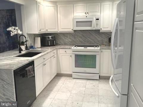 kitchen featuring decorative backsplash, white appliances, white cabinetry, and sink