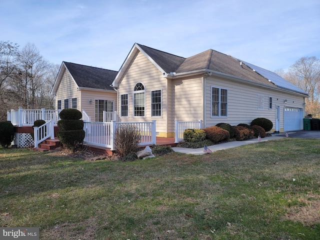 view of front of home featuring a wooden deck, a front lawn, a garage, and solar panels