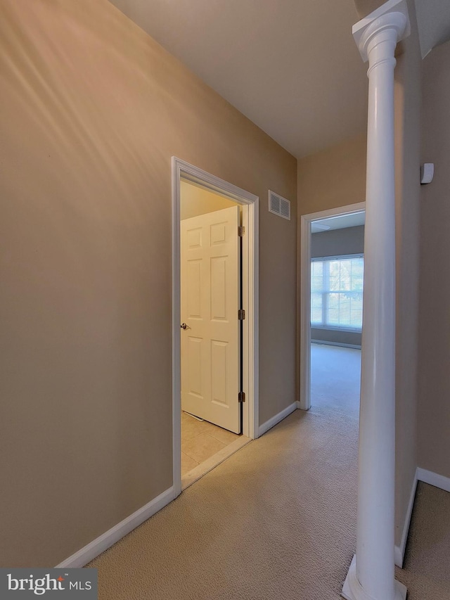 hall featuring light carpet and decorative columns