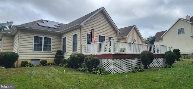 back of house featuring solar panels, a yard, and a wooden deck