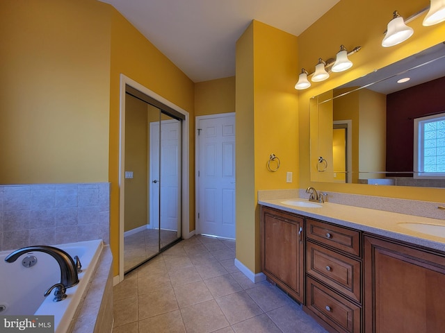 bathroom with tile patterned flooring, vanity, and a relaxing tiled tub