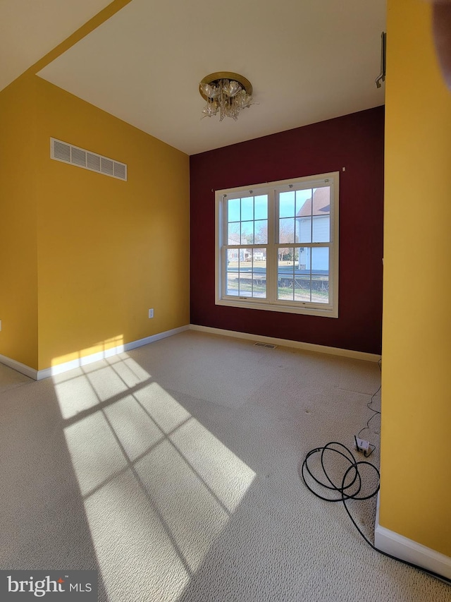 spare room with carpet and a notable chandelier