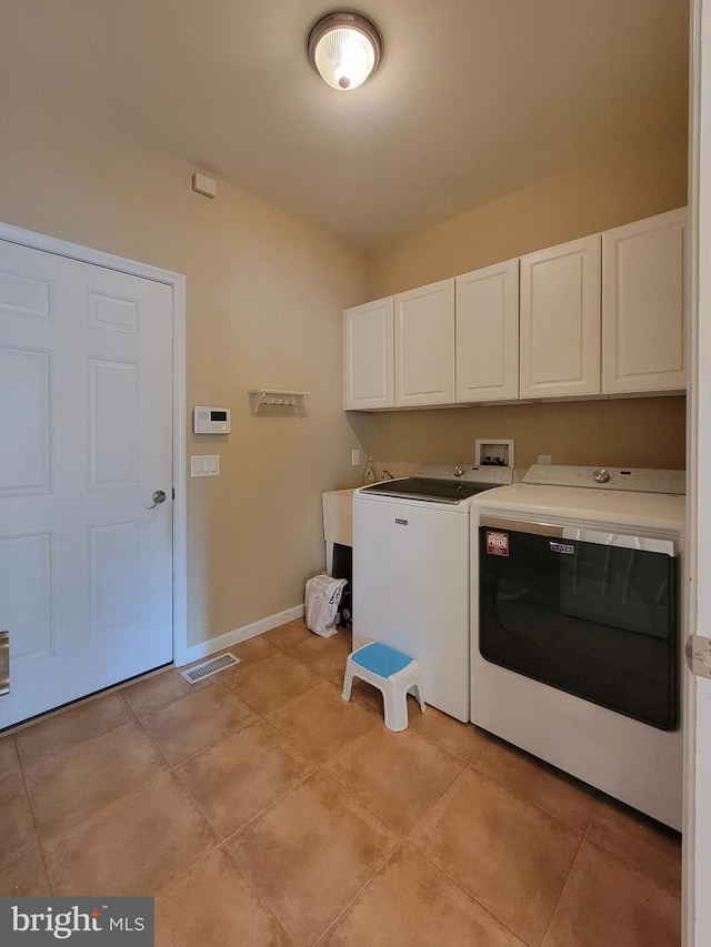 laundry room with cabinets, light tile patterned floors, and separate washer and dryer