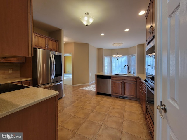 kitchen with sink, a notable chandelier, kitchen peninsula, decorative light fixtures, and appliances with stainless steel finishes