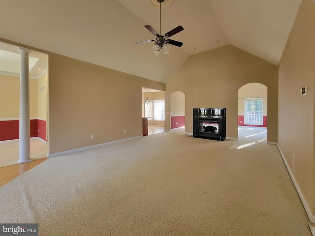 unfurnished living room featuring light carpet, high vaulted ceiling, ceiling fan, and ornate columns