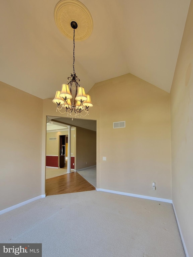 spare room with carpet, lofted ceiling, and an inviting chandelier