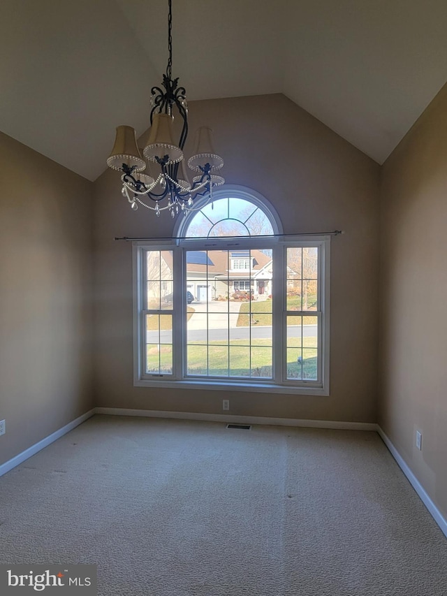 spare room featuring a chandelier, carpet flooring, and lofted ceiling