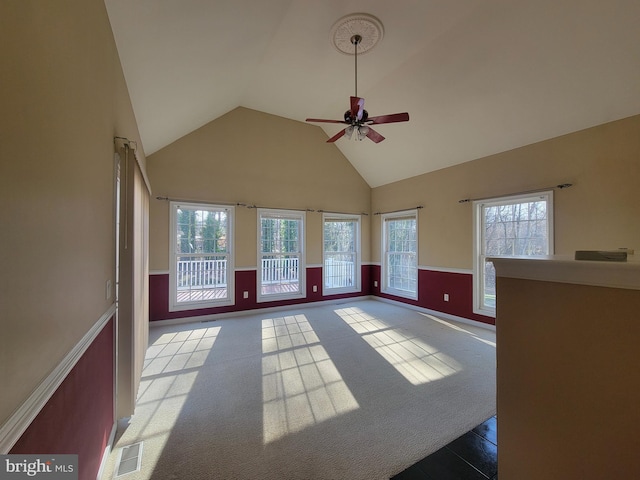 unfurnished living room with carpet floors, high vaulted ceiling, and ceiling fan