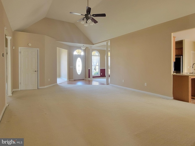 carpeted entrance foyer with ceiling fan and high vaulted ceiling