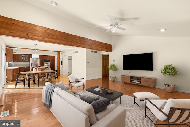 living room featuring ceiling fan, lofted ceiling, light wood-type flooring, and sink