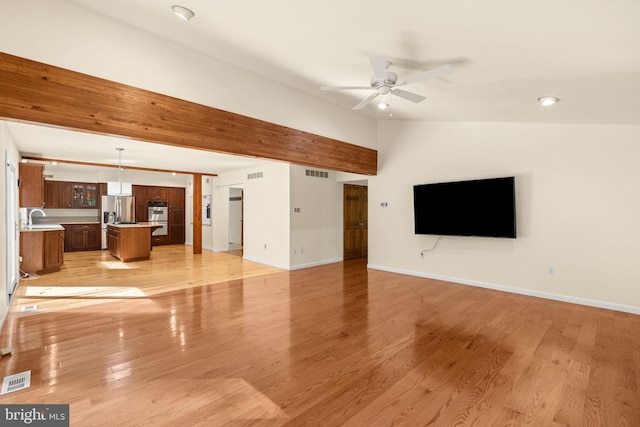 unfurnished living room with ceiling fan, vaulted ceiling, sink, and light hardwood / wood-style floors