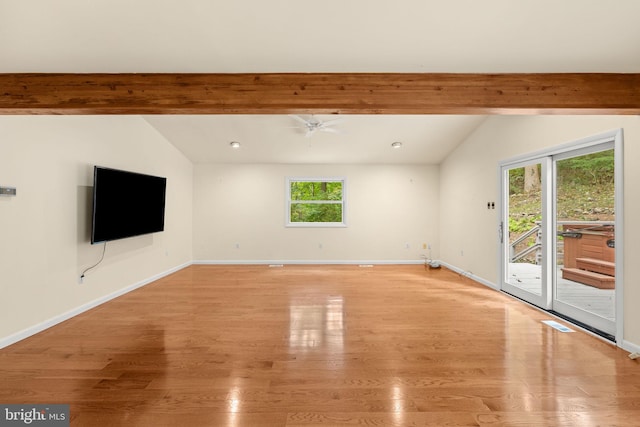 unfurnished living room with ceiling fan, vaulted ceiling with beams, light wood-type flooring, and a wealth of natural light