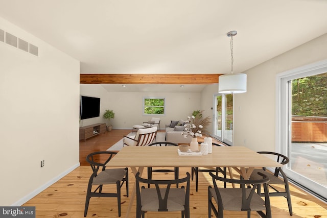 dining room with beamed ceiling and light wood-type flooring