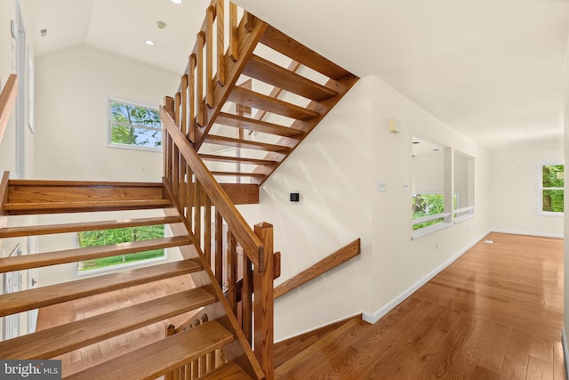 stairs with lofted ceiling, plenty of natural light, and wood-type flooring