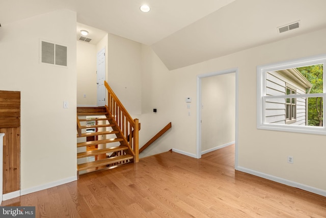 stairway with hardwood / wood-style flooring and lofted ceiling