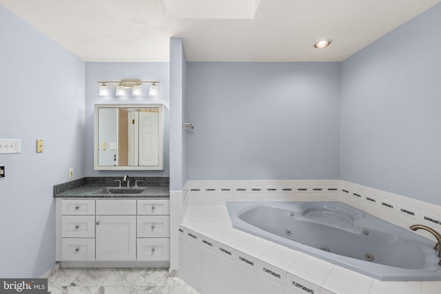 bathroom featuring a skylight, vanity, and tiled bath