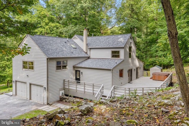 rear view of house with a storage unit, a deck, and a garage