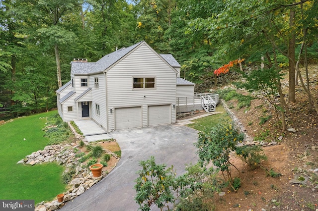 view of property exterior featuring a garage, a deck, and a lawn