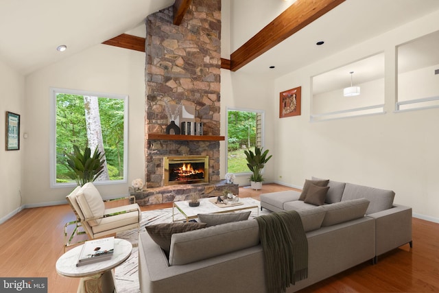 living room with high vaulted ceiling, beam ceiling, hardwood / wood-style flooring, and a stone fireplace