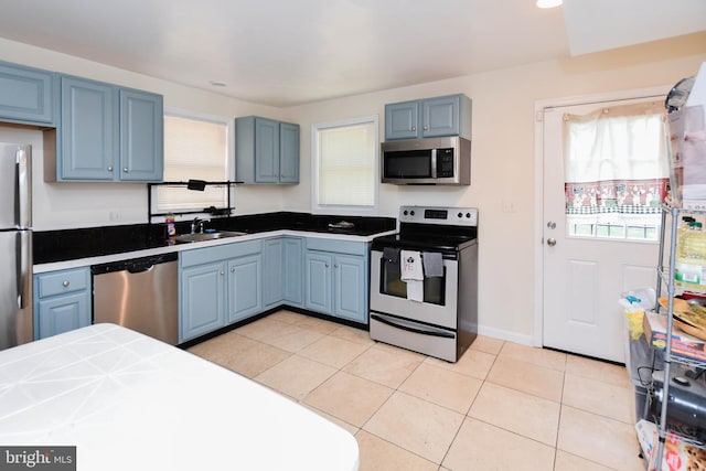 kitchen with tile counters, appliances with stainless steel finishes, light tile patterned flooring, and sink