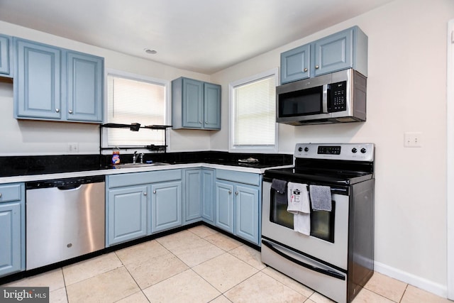 kitchen with blue cabinets, appliances with stainless steel finishes, light tile patterned flooring, and sink