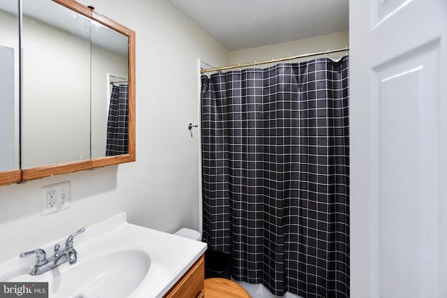 bathroom with walk in shower, vanity, and toilet