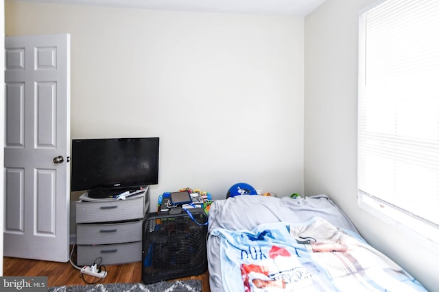 bedroom with multiple windows and dark wood-type flooring