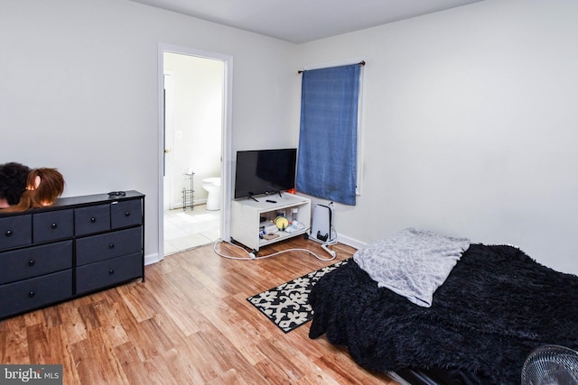 bedroom with connected bathroom and light hardwood / wood-style floors