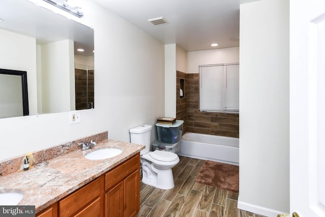 full bathroom featuring tiled shower / bath, vanity, and toilet