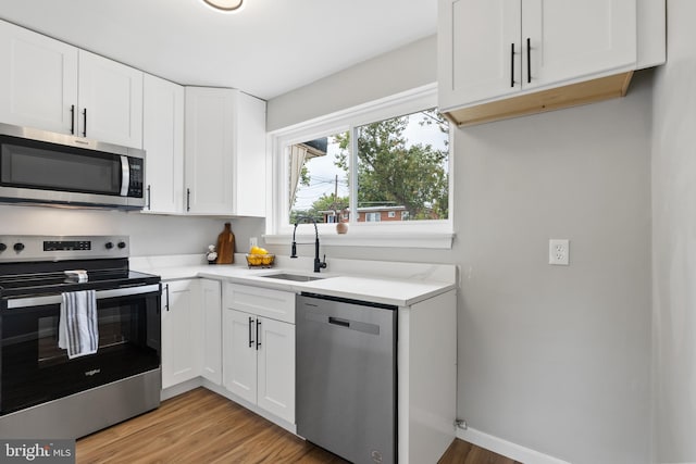 kitchen featuring light wood-type flooring, sink, stainless steel appliances, and white cabinets