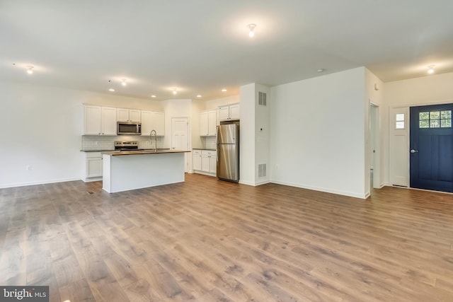 kitchen featuring an island with sink, stainless steel appliances, white cabinetry, and light wood-type flooring