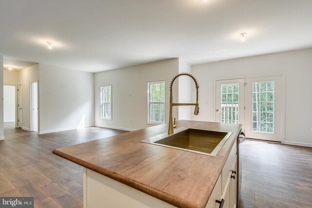 kitchen featuring a center island, hardwood / wood-style floors, sink, and white cabinetry