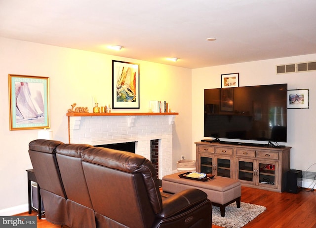 living room with hardwood / wood-style floors and a brick fireplace