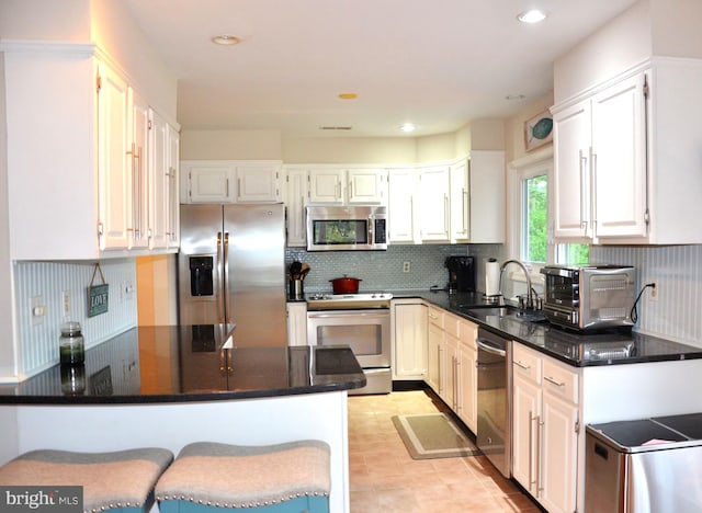 kitchen with white cabinetry, kitchen peninsula, appliances with stainless steel finishes, and sink