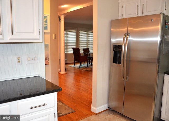 kitchen featuring stainless steel refrigerator with ice dispenser, light wood-type flooring, decorative columns, and white cabinetry