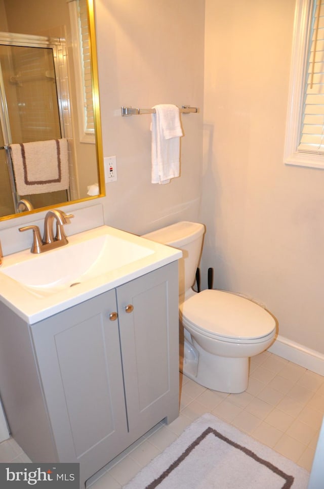 bathroom with vanity, a shower with shower door, toilet, and tile patterned floors