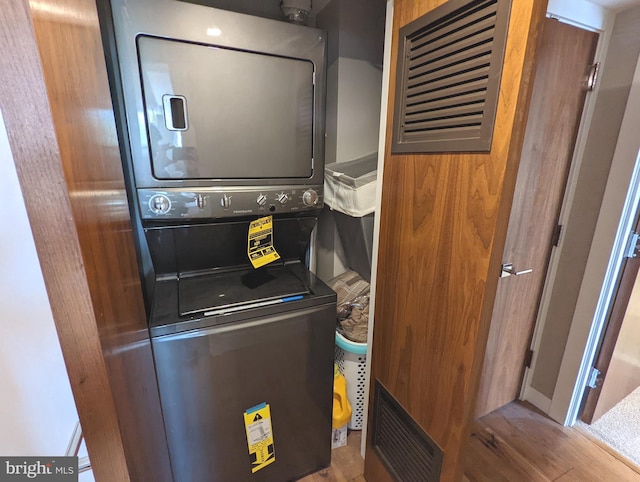 laundry area with stacked washer / dryer and hardwood / wood-style floors